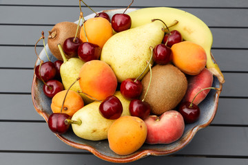 Wall Mural - Pears, apricots, cherries, kiwis and banana in a bowl