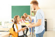 © Pixel-Shot - Father giving little girl a book in classroom