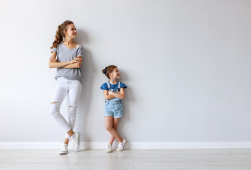 happy family mother (big sister) and child daughter near an empty wall.