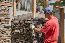 Man Building Stone Wall For House Construction
