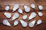 Several led bulbs of different sizes and different bases on a wooden background.