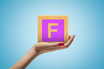 Fototapete - Female hand holding alphabet toy block on blue background
