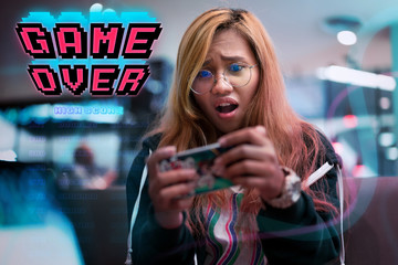 Young Asian gamer girl playing mobile games on smartphone device - Female player losing online wireless multiplayer phone game with game over graphic - app, entertainment and lifestyle concept