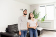 © pressmaster - Smiling curious young couple in casual outfits standing in room