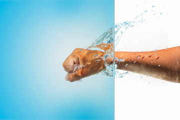 Wall Mural - a Male fist strikes in blue water and splashes of drops fly on a white background