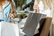Women holding shopping bags outdoors while shopping, close-up view on the empty paper bags with copy space