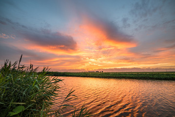 Wall Mural - colorful clouds in the sky at sunset. beautiful reflections and waves in the water of a river.