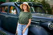 Portrait of a young woman in an old car . The girl wears jeans wide-brimmed hat and a light blouse