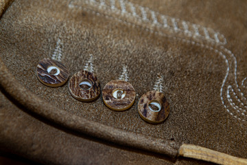 close up of an alpine leather trouser with stag horn button