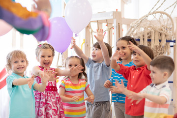 active children having fun and playing with multicolored balloons in daycare