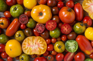 Close up of colorful tomatoes, some sliced, shot from above