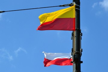 Flag of Warsaw (horizontal bands: yellow and red ) and Flag of Poland (two  bands: white and red). Flags hanging on the pole displayed in public places on national holidays and other important days