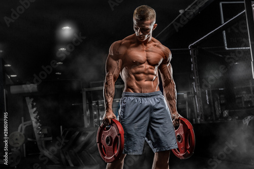 Young male athlete bodybuilder posing and doing sports exercises in the gym Fototapet
