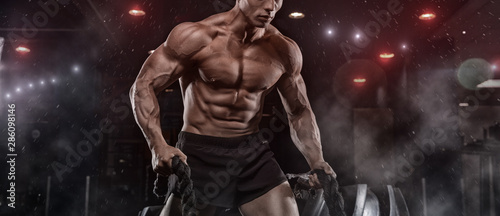 Fotomural Male athlete bodybuilder posing on a black background