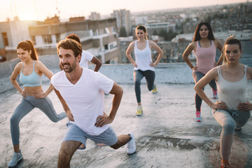 Wall Mural - Group of fit healthy friends, people exercising together outdoor on rooftop