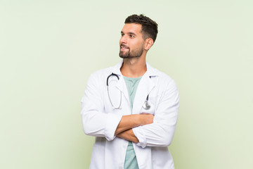 Wall Mural - Young doctor man over isolated green wall laughing