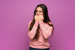 Teenager girl over purple wall nervous and scared putting hands to mouth