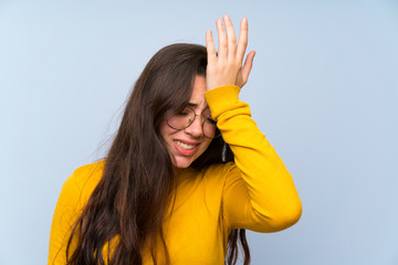 Wall Mural - teenager girl over isolated blue wall having doubts with confuse face expression