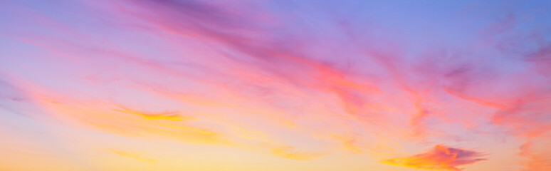 panorama of the sunset sky with pink and golden layered clouds. natural heaven background. beautiful