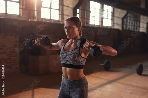 Fotomural Sport woman doing fitness exercise with dumbbells at gym