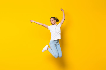 Young woman jumping over isolated yellow wall