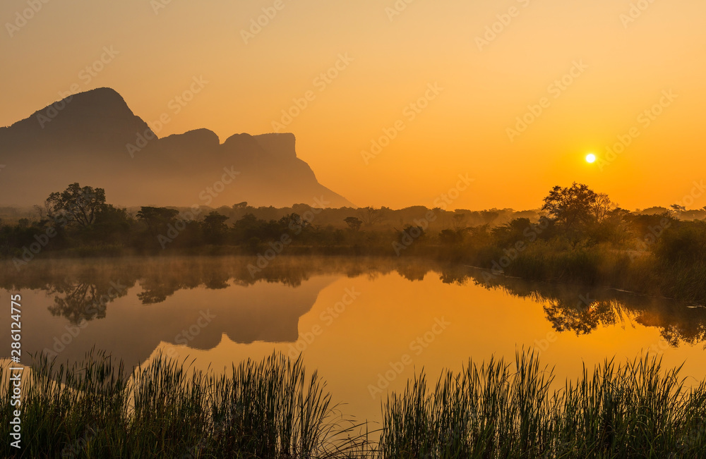 Landscape of the Hanging Lip or Hanglip mountain peak at sunrise with mist hanging above a swamp lake inside the Entabeni Safari Game Reserve, Limpopo Province, South Africa. - obrazy, fototapety, plakaty 