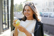 © shurkin_son - People, age, modern lifestyle, summertime and food concept. Attractive cheerful middle aged Caucasian woman wearing trendy black leather jacket smiling broadly, eating ice cream cone on street