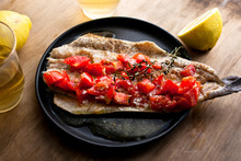 Close up of baked trout with tomatoes and thyme served on plate
