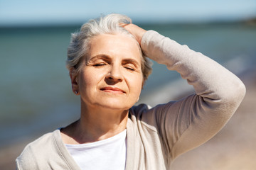 Sticker - people and leisure concept - portrait of happy senior woman enjoying sun on beach