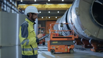 Wall Mural - Heavy Industry Engineer Walk Through Pipe Manufacturing Factory, Use Digital Tablet Computer. Facility for Construction of Oil, Gas and Fuel Pipeline Transportation Products. Side View Slow Motion