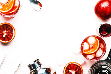 Trendy alcoholic cocktail Negroni with dry gin, red vermouth and red bitter, orange slice and ice cubes. White background, bar tools, top view, copy space