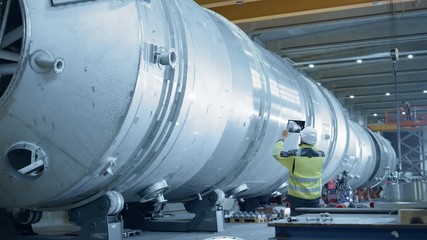Wall Mural - Heavy Industry Engineer Uses Augmented Reality Digital Tablet to Scan Large Diameter Pipe. Modern Industrial Manufacturing Technology to Design and Construct Oil, Gas and Fuels Transport Pipeline.