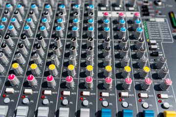 Close up photo of a professional sound mixer with many adjustments, knob switches and buttons of audio mixer control panel.