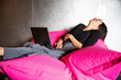 © Mat Hayward - Woman laughing with laptop computer  while sitting on pink beanbag chair