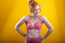 Cute Girl With Red Hair And Freckles Wearing A Pink Polka Dot Bikini With A Yellow Background