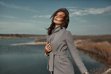 Fototapeta Tulipany - Beautiful elegant portrait of young woman in fashion grey coat outside. Sunny autumn ar spring weather.