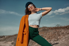 Autumn Fashion. Beautiful Attracrive Young Woman In Bright Autumn Look. Orange Trendy Coat And Pants And Fashion Sunglasses.