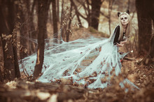 Portrait Of Female With Skull Make Up In Spider Web With Dreadblocks And Horns At Autumn Forest. Mysterious Model Girl With Halloween Make Up