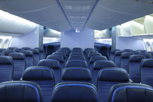 Empty Commercial Airplane Cabin Interior With Blue Leather Seats. Two Aisles And Open Overhead Bins