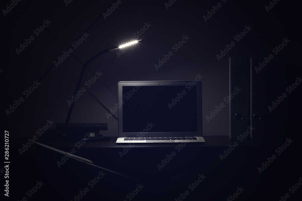 Modern workplace with laptop in evening - obrazy, fototapety, plakaty 