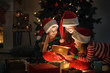 © Pixel-Shot - Cute little children opening magic Christmas gift at home