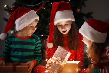 Cute little children opening magic Christmas gift at home