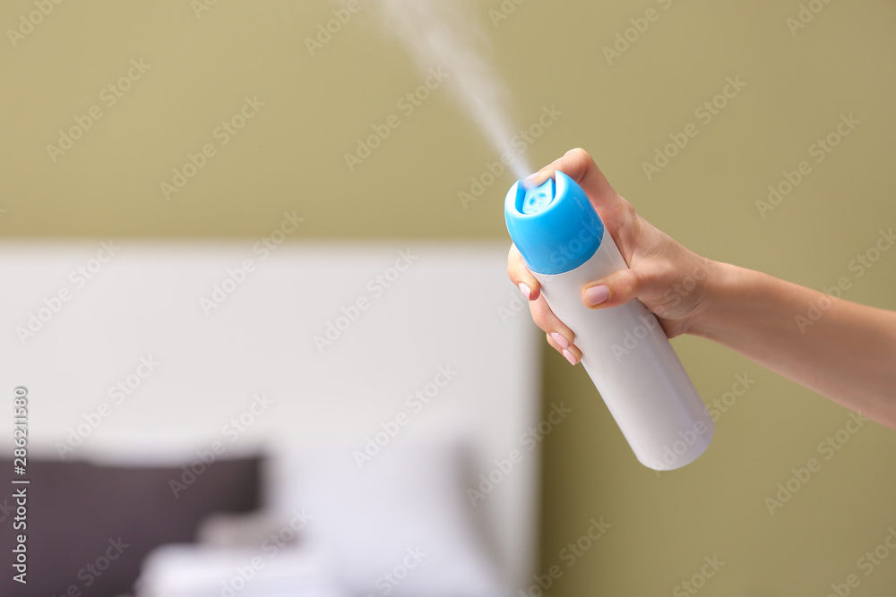 Woman using air freshener at home