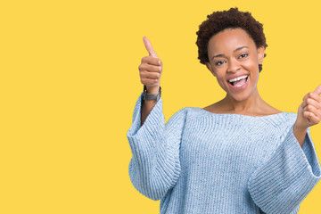 Young beautiful african american woman wearing a sweater over isolated background approving doing positive gesture with hand, thumbs up smiling and happy for success. Looking at the camera