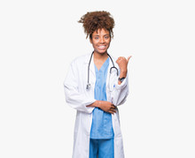 Young African American Doctor Woman Over Isolated Background Smiling With Happy Face Looking And Pointing To The Side With Thumb Up.
