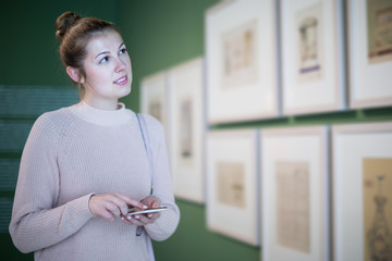 Sticker - Positive woman visitor using mobile in museum