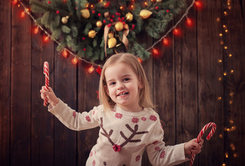 Wall Mural - little girl with christmas decorations on dark wooden background