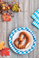 Oktoberfest rustic background with prezel in paper plate and Autumn leaves