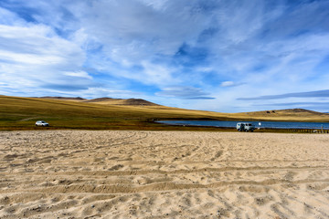 Lake Baikal, hills and sand with beautiful sky and clouds and 2 cars, Russia Oklhon island