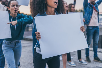 cropped view of emotional multicultural girls screaming and holding blank placards during protest